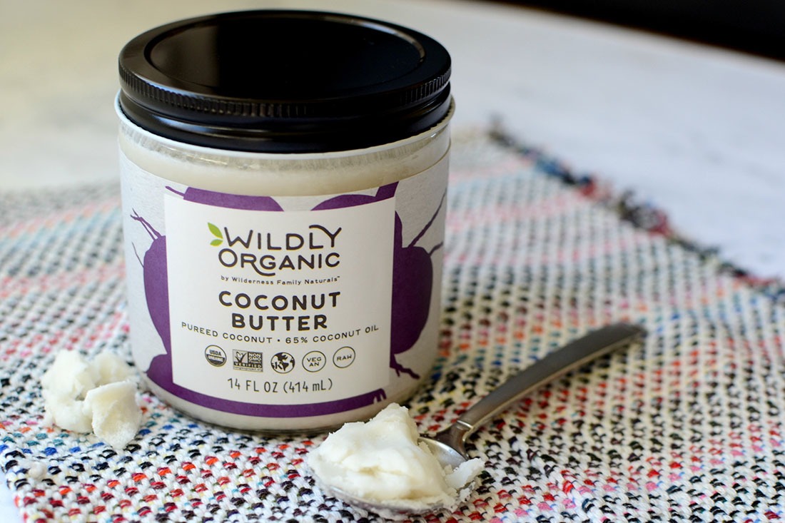 Jar of Wildly Organic Coconut Butter on a colorful cloth with some butter on a spoon