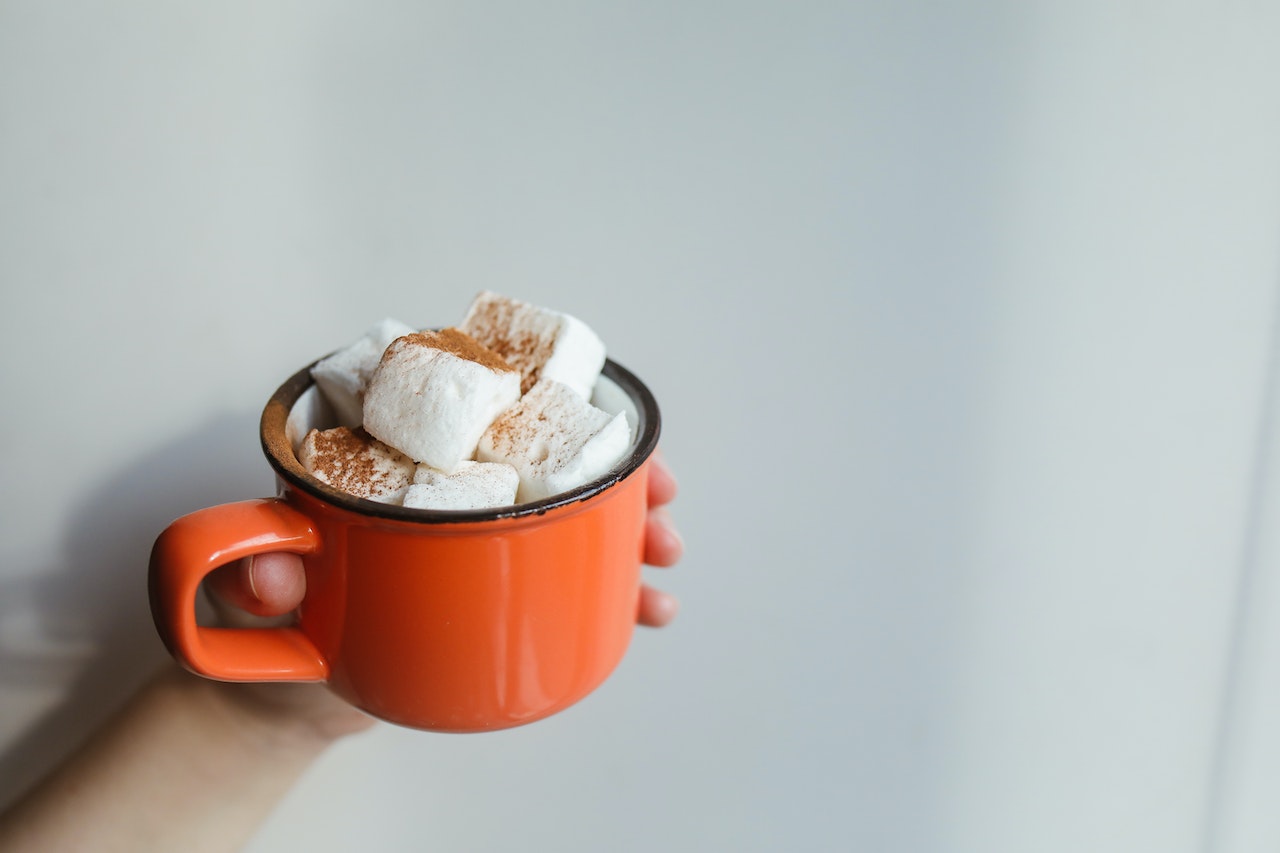A person holding a mug of hot cacao