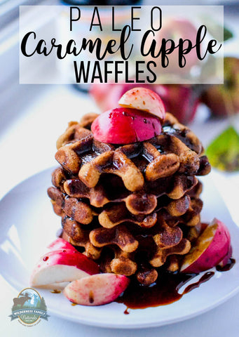 Stack of paleo caramel apple waffles with syrup and apple slices on a white plate