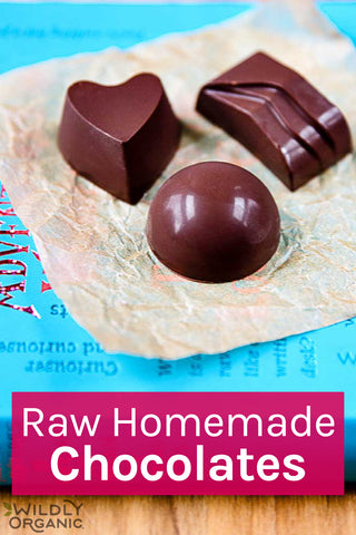 Assorted raw homemade chocolates on parchment with text Raw Homemade Chocolates from Wildly Organic